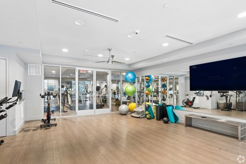 A spacious gym with a variety of exercise equipment and a television.