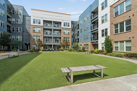 A park area with a bench in front of apartment buildings.
