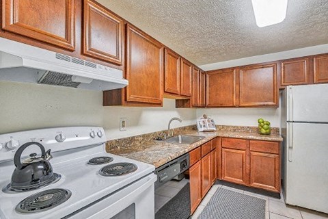 A kitchen with a white stove and wooden cabinets.