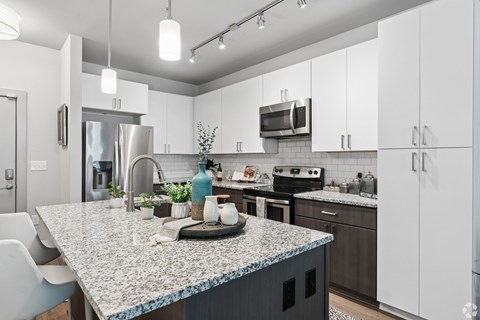 A kitchen with a granite countertop and white cabinets.