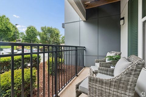 A balcony with a black railing and a wicker chair.