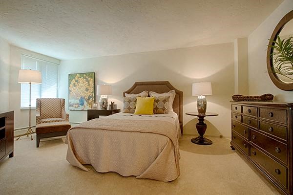 A bedroom with a large bed, a chair, and a painting on the wall.