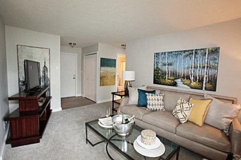 A living room with a couch, coffee table, and a painting on the wall.