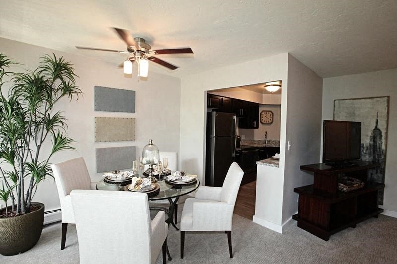 A dining room with a table set for six with a plant in a pot on the left.