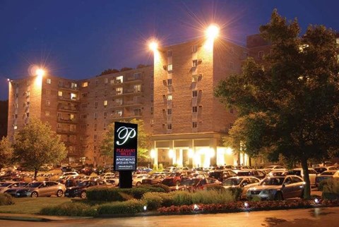 A parking lot in front of a large apartment building at night.