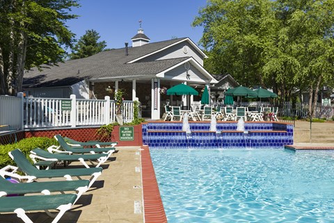A pool with chairs and a building in the background.