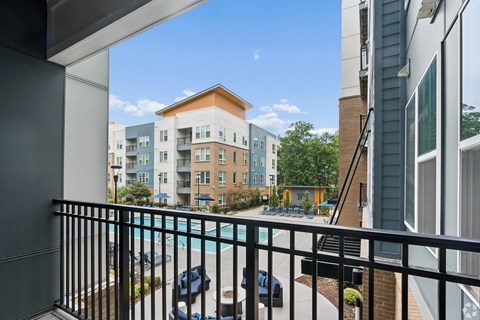 A balcony overlooks a pool and apartment buildings.