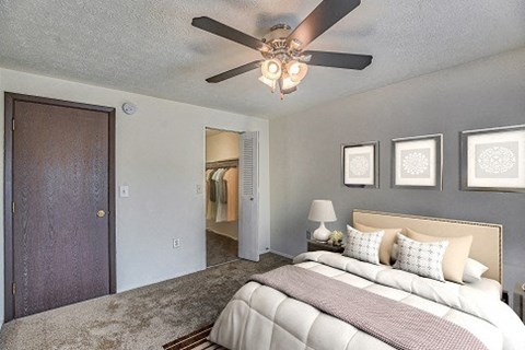 A bedroom with a bed, a ceiling fan, and pictures on the wall.