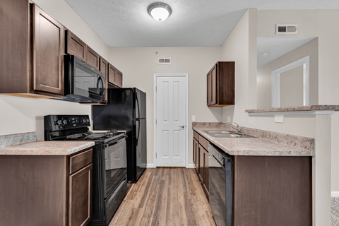 A kitchen with brown cabinets and a black refrigerator.