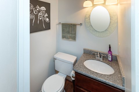 A bathroom with a toilet, sink, and a mirror.