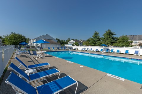 A pool with blue chairs and a white fence.