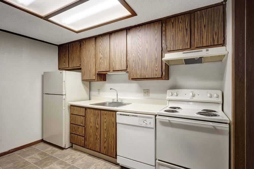 A kitchen with white appliances and wooden cabinets.