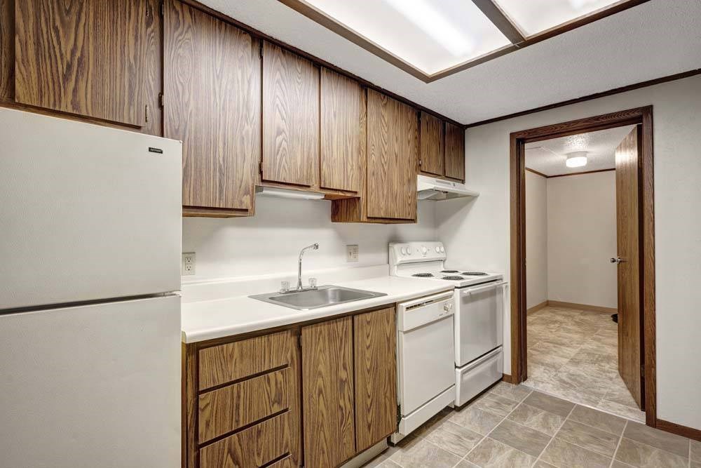 A kitchen with white appliances and wooden cabinets.