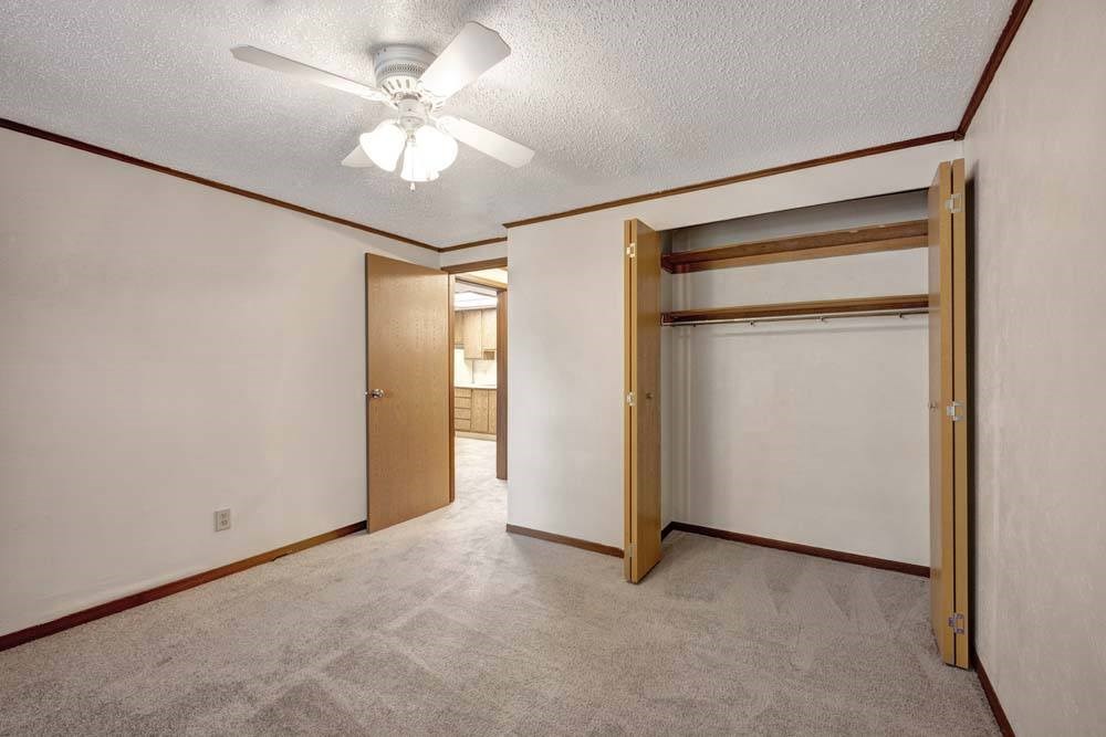 A room with a ceiling fan and a closet with a sliding door.