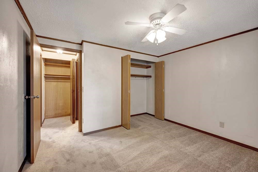 A room with a ceiling fan and carpeted floor.