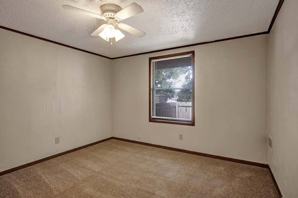 A room with a ceiling fan and a window with a view of a building outside.