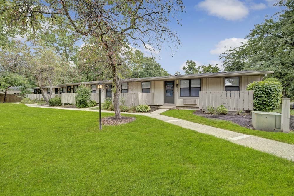 A tree stands in a grassy area in front of a building.