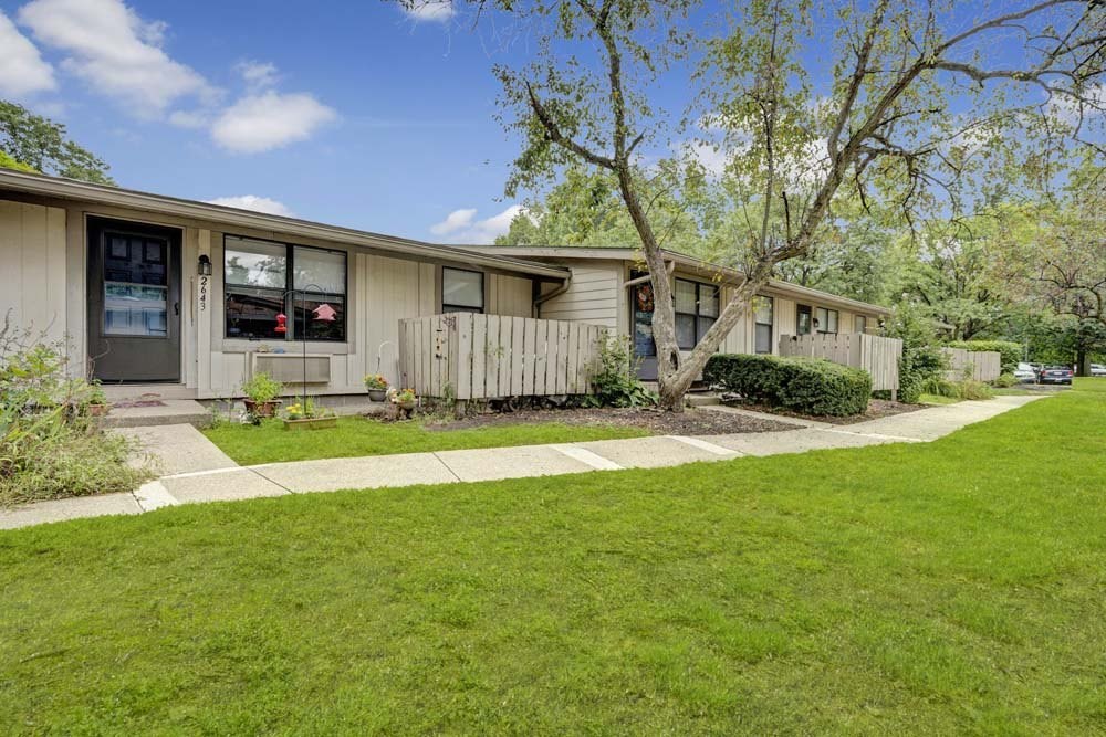 A row of houses with green lawns and trees.