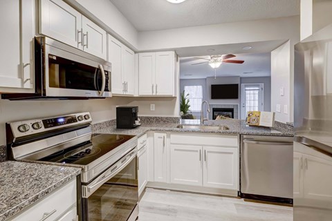 A kitchen with white cabinets and granite countertops.