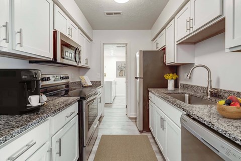 A kitchen with white cabinets and a black microwave.