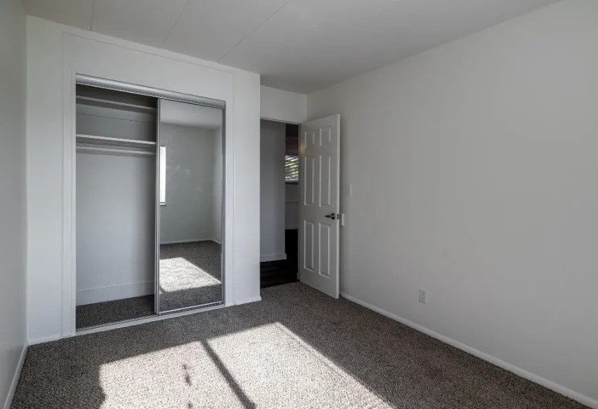 A room with a white door and a mirror on the wall.