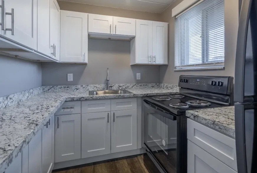 A kitchen with granite countertops and white cabinets.