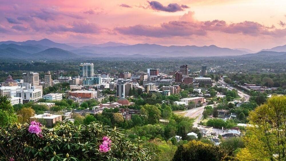 A cityscape with buildings and a mountain range in the background.