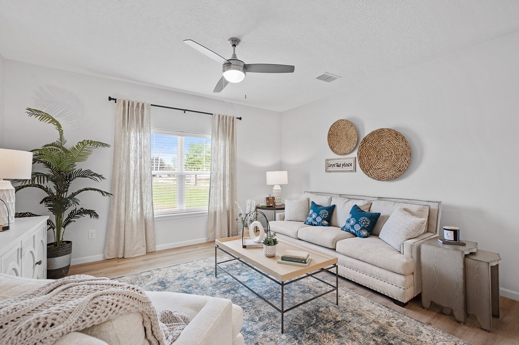 A living room with a white couch, a coffee table, and a ceiling fan.