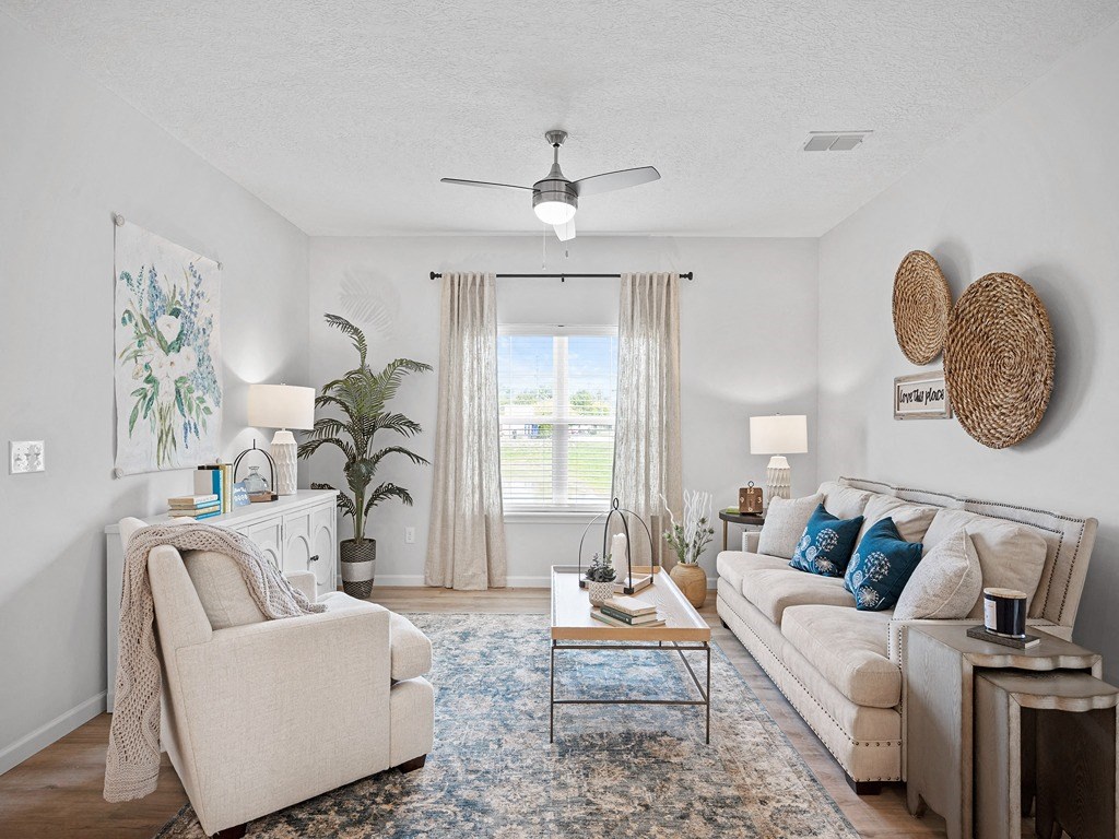 a living room with couches and chairs and a ceiling fan