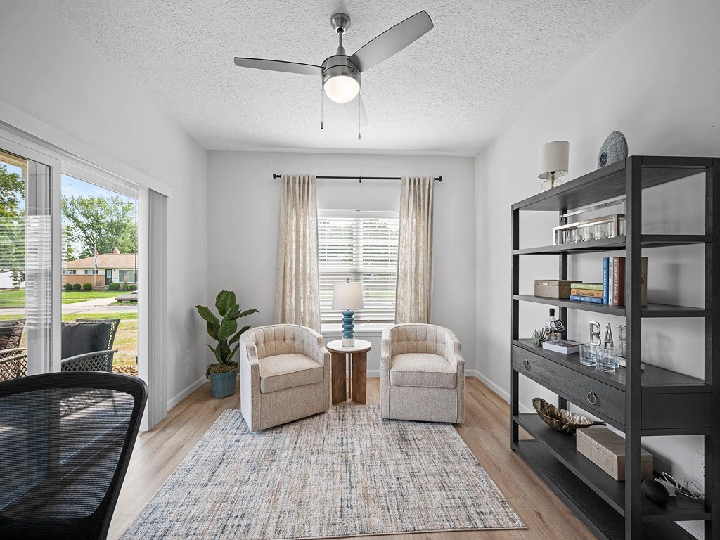 a living room with two chairs and a ceiling fan