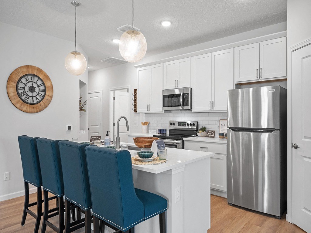 a kitchen with a island and a stainless steel refrigerator