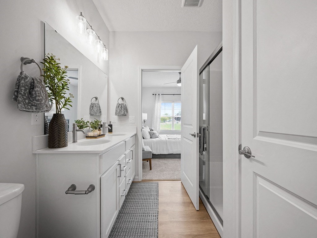 a white bathroom with a white counter top and a glass shower