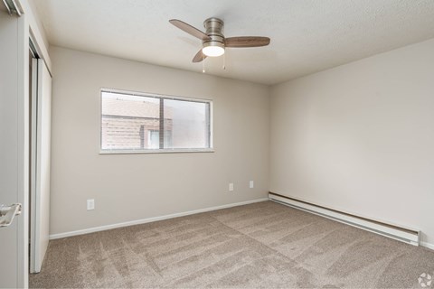 A room with a ceiling fan and a window with blinds.
