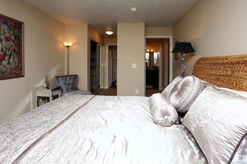 A bedroom with a large bed and a chair.