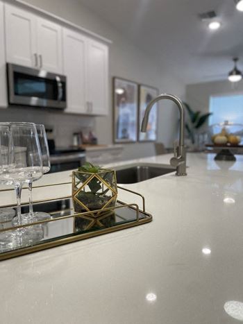 a kitchen with a sink and a counter with wine glasses