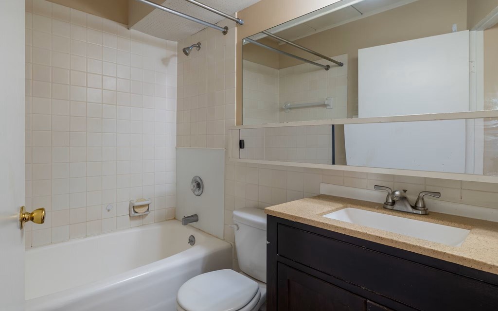 A white toilet sits next to a white bathtub in a bathroom.
