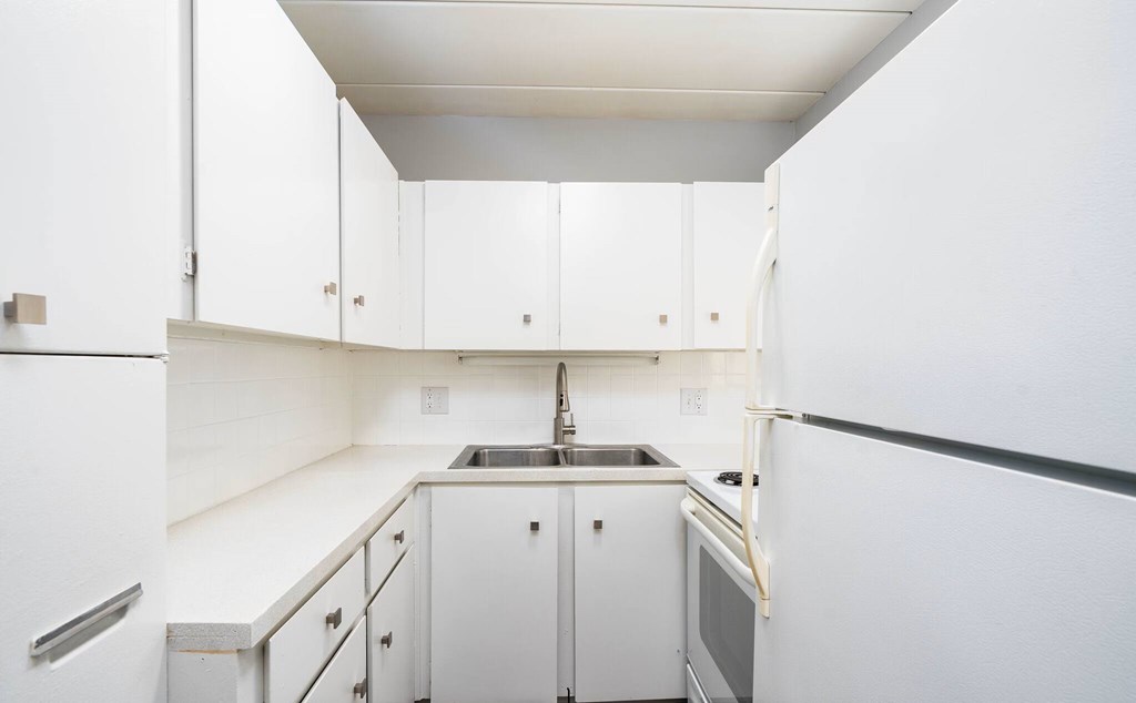 A kitchen with white cabinets and appliances.