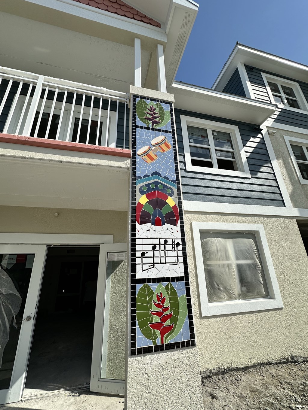 A mosaic on a building with a white door and a window.