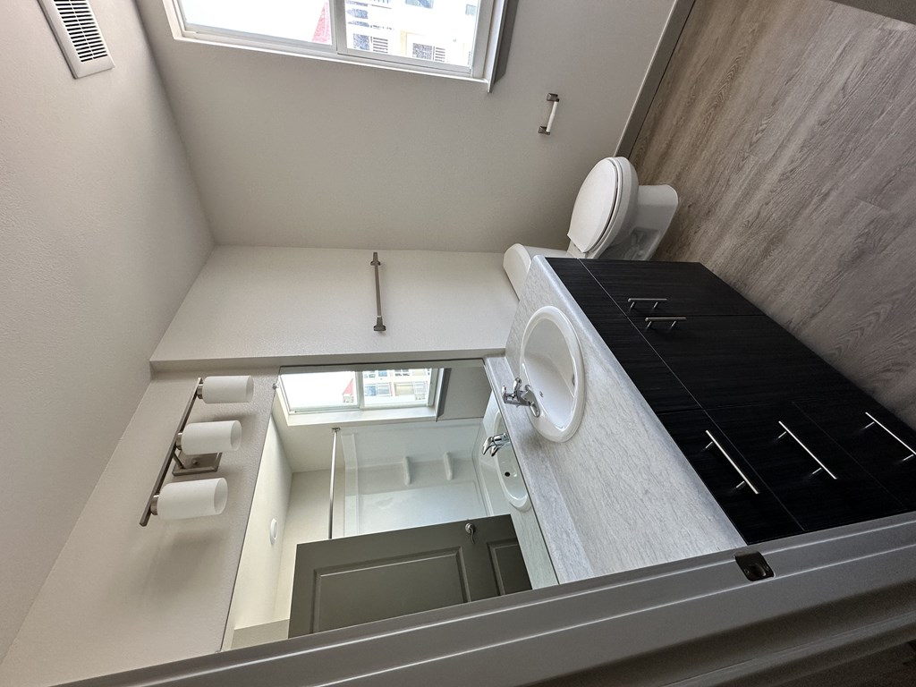 A bathroom with a toilet, sink, and a window.
