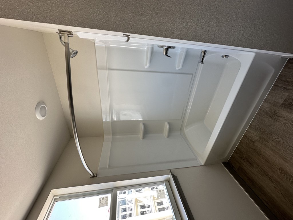 A white bathtub with a shower head and a glass door.