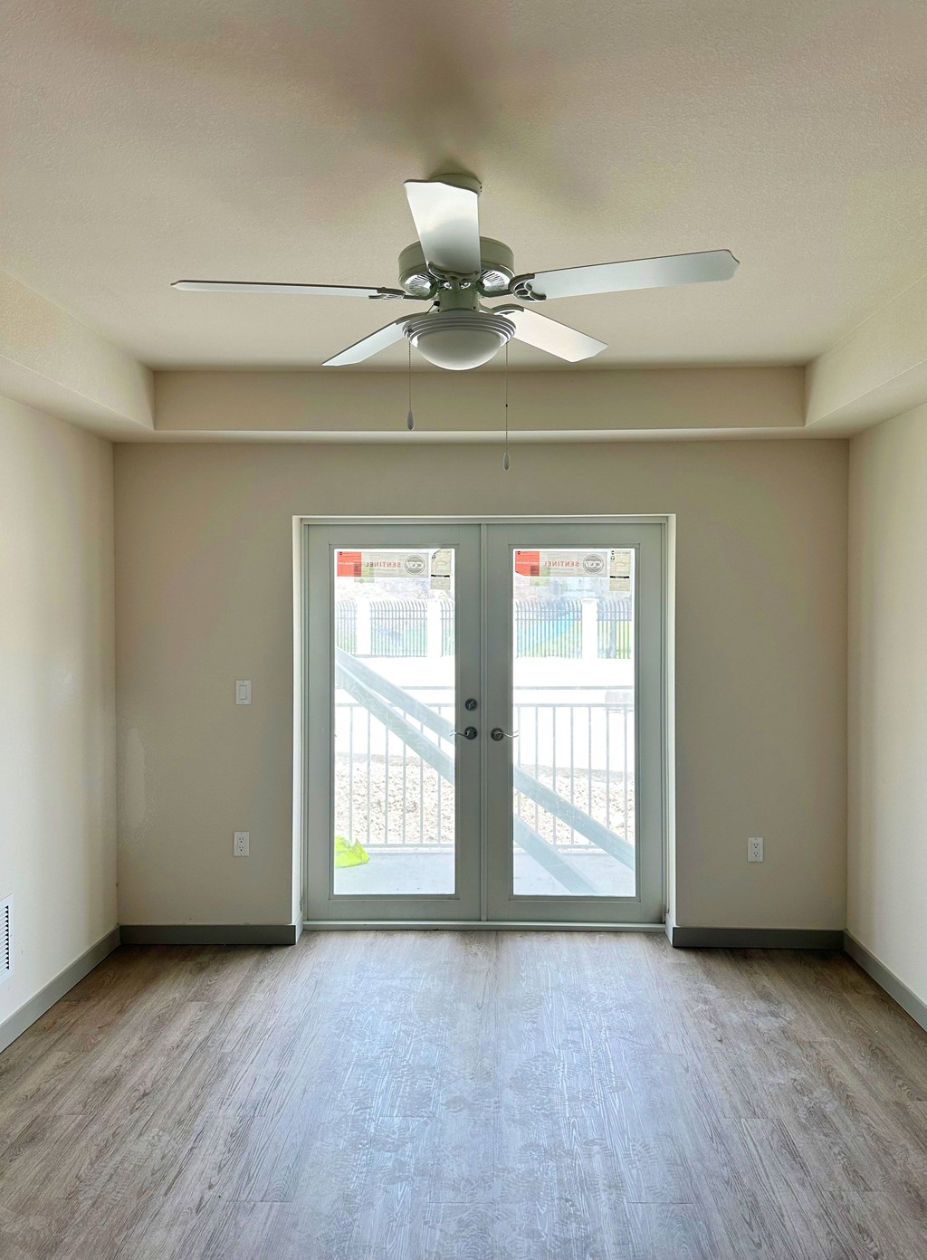 A room with a ceiling fan and a door leading outside.