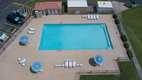 An aerial view of a swimming pool surrounded by sun loungers and umbrellas.