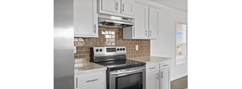 A modern kitchen with a stove top oven and white cabinets.