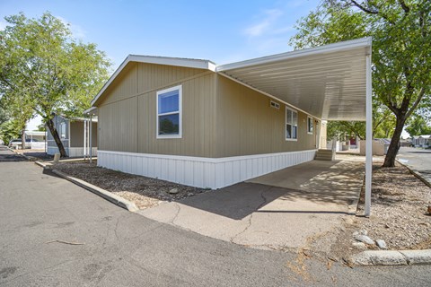 A beige house with a white roof and a white fence.