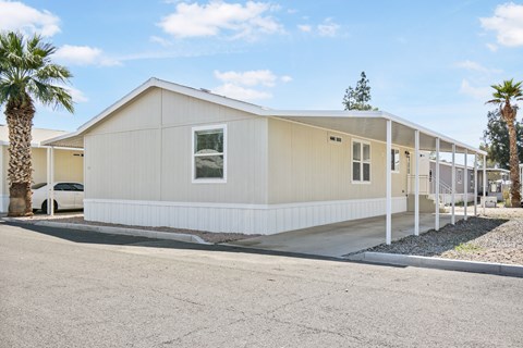 A beige house with a white fence and a car parked in front.