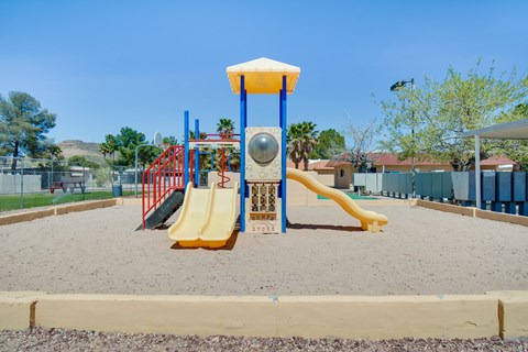 A playground with a yellow slide and a red and blue structure.