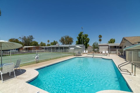 A swimming pool with a sun lounger and a fence.