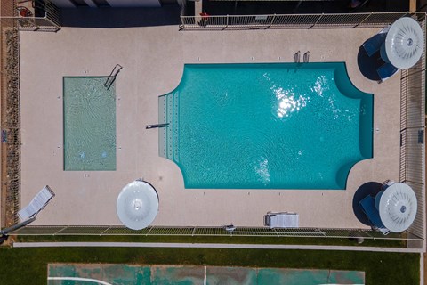 An aerial view of a swimming pool with a diving board and a small pool next to it.