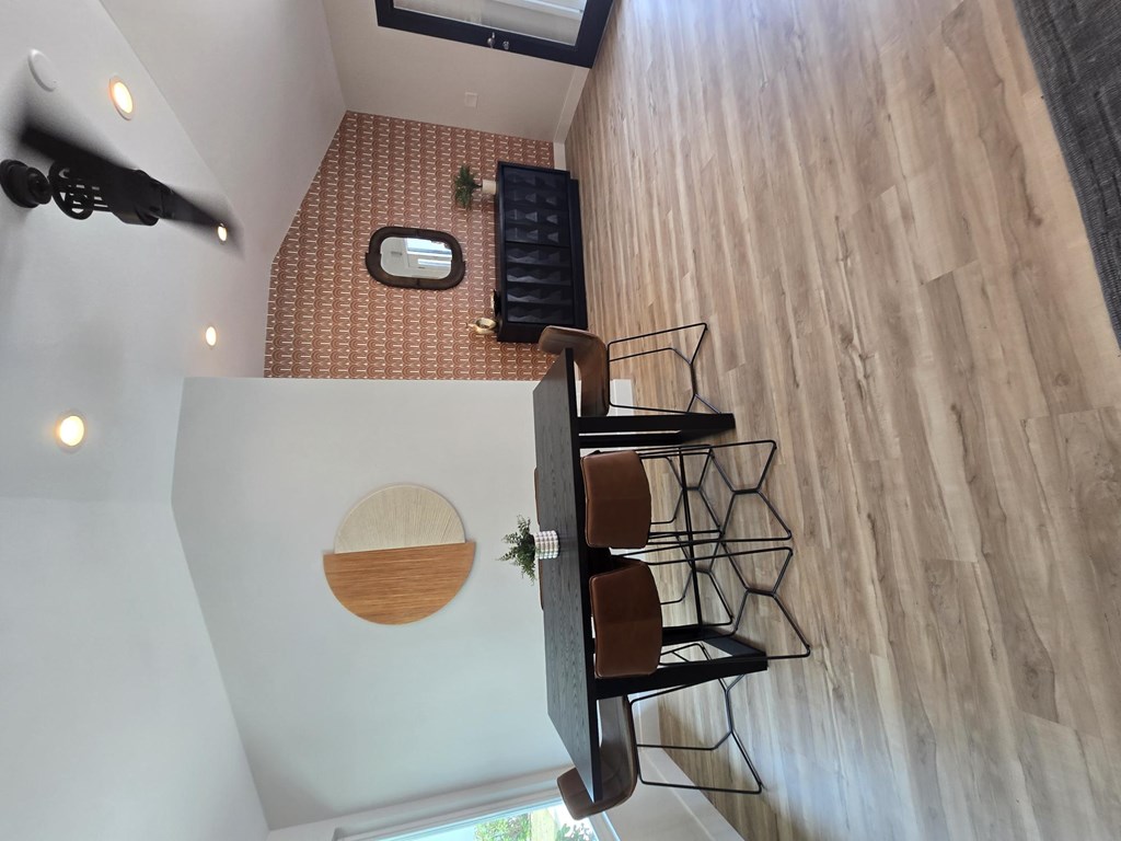A wooden table with chairs and a small mirror on the wall.
