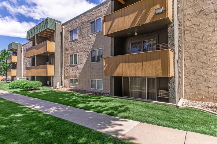 A modern apartment building with a green lawn in front.